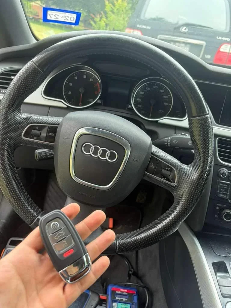 A key held beside an Audi steering wheel
