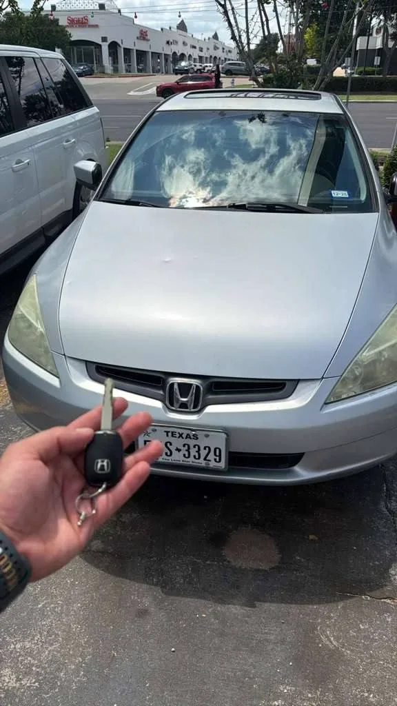 A car key held in front of a silver Honda